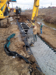 The geocell retaining wall footing layer is installed and granular infill is placed.