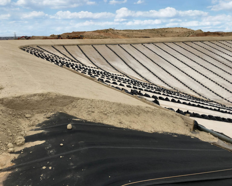 Deploying a geosynthetic mattress ballast layer at an oreprocessing