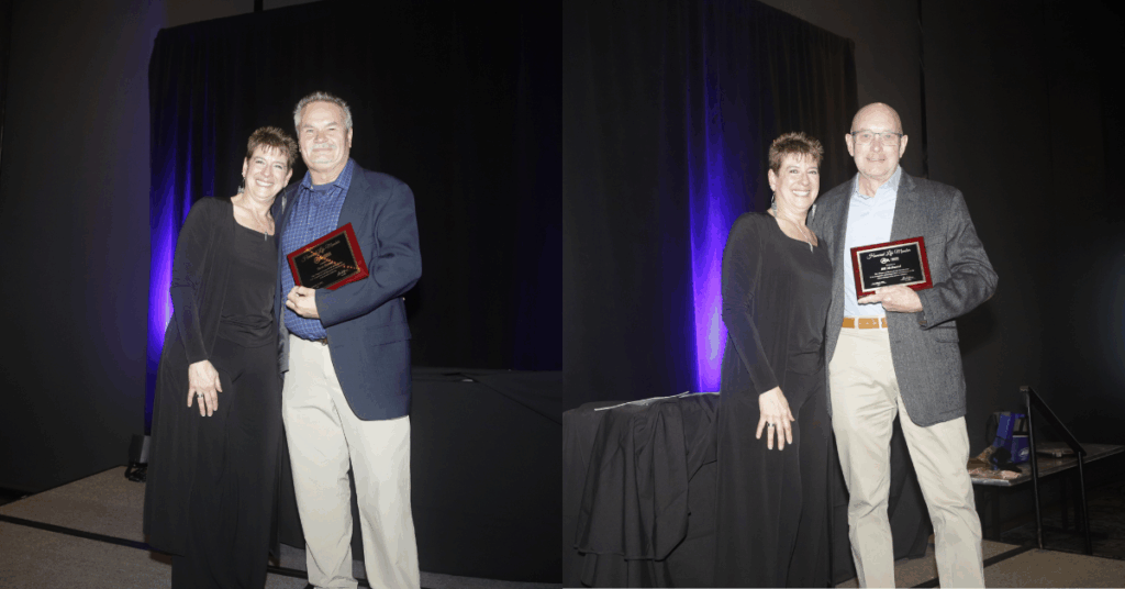 Two recipients holding plaques stand beside each other, smiling. The backdrop is dark with purple lighting, enhancing the celebratory mood.